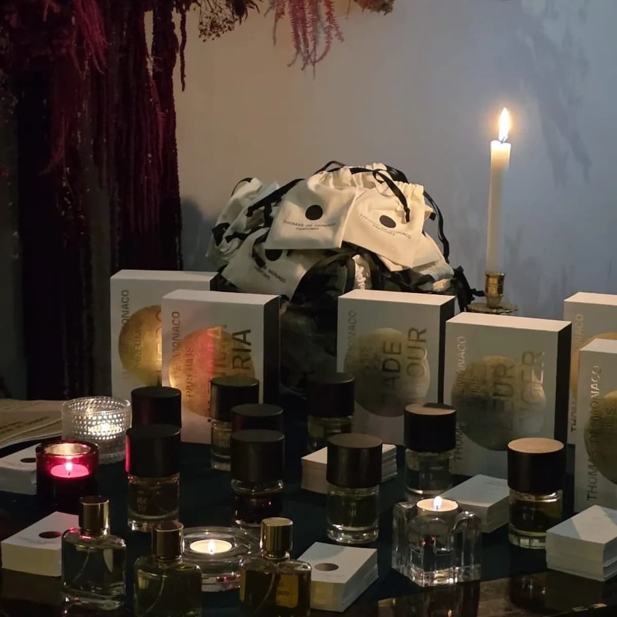 Niche perfume bottles and boxes laid out by candlelight at a brand evening