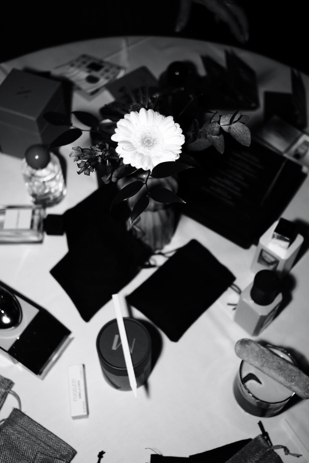 A table of perfumes, samples and a single flower seen from above