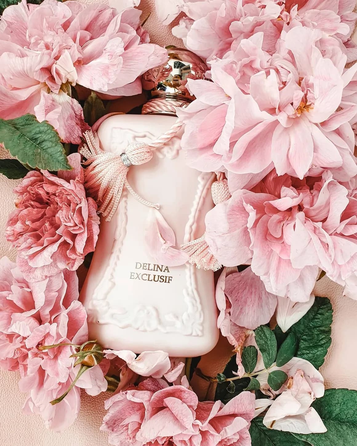 Pale pink ceramic bottle nested in fresh peonies