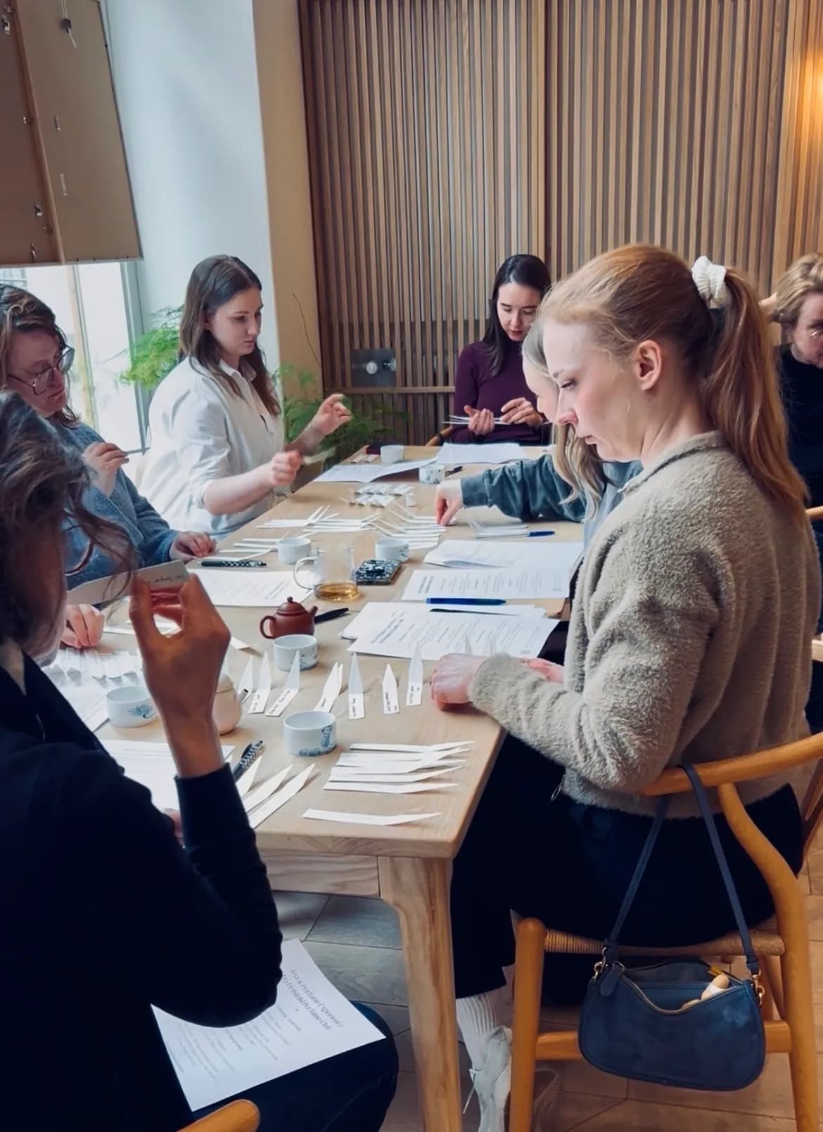 Guests tasting tea and smelling blotters around the table at a Tea & Perfume Experience