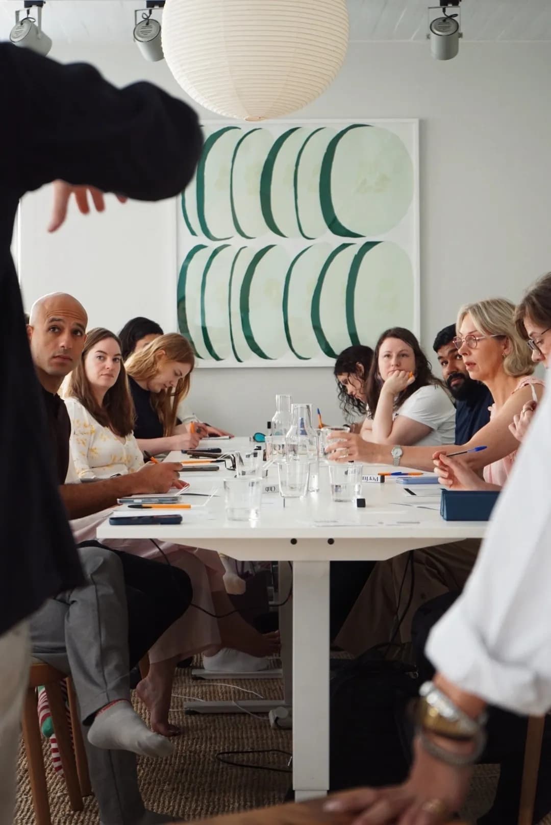 A long table of people taking notes at a daylit scent training session