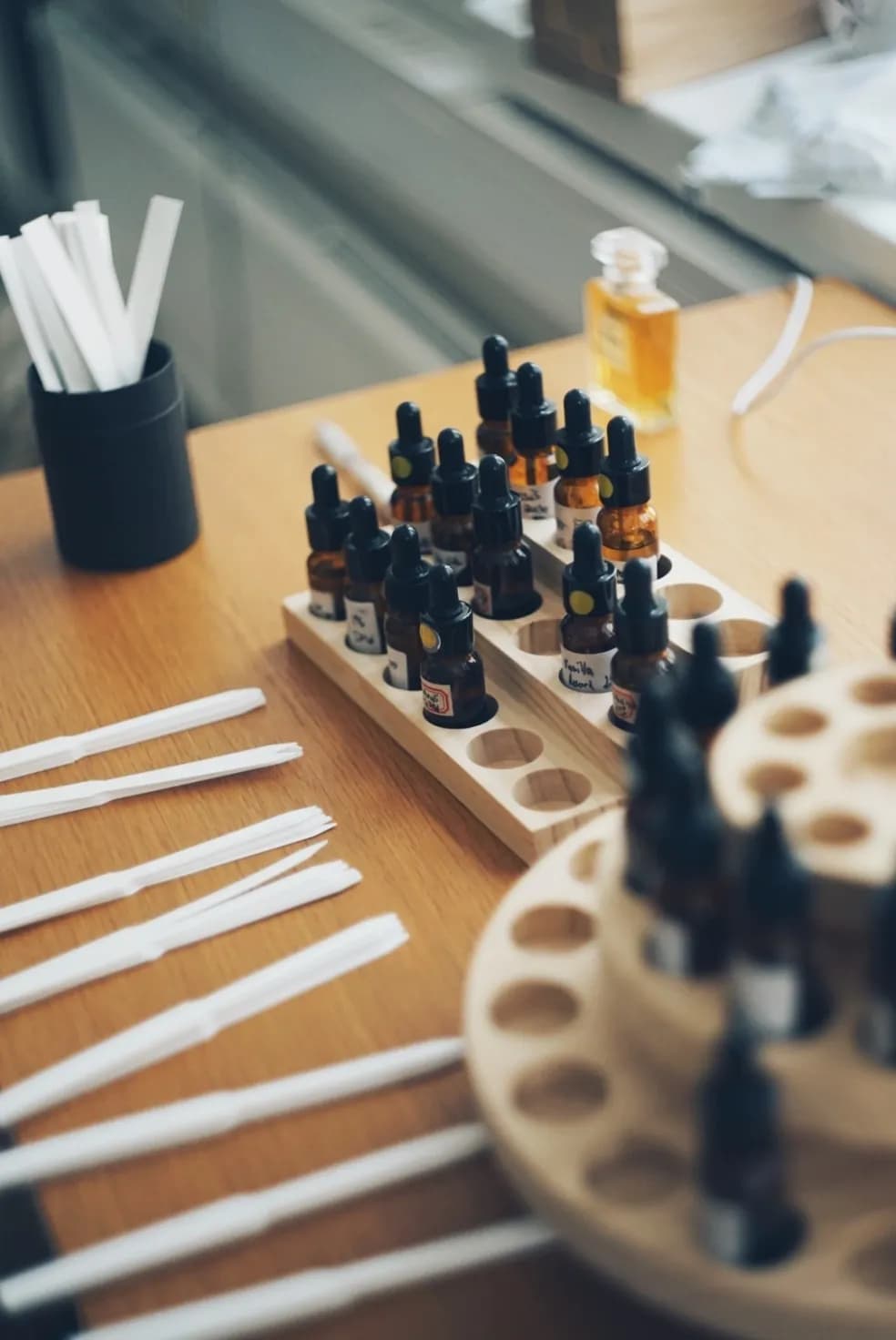 Amber dropper bottles of perfume materials in wooden racks, with blotters laid out beside them